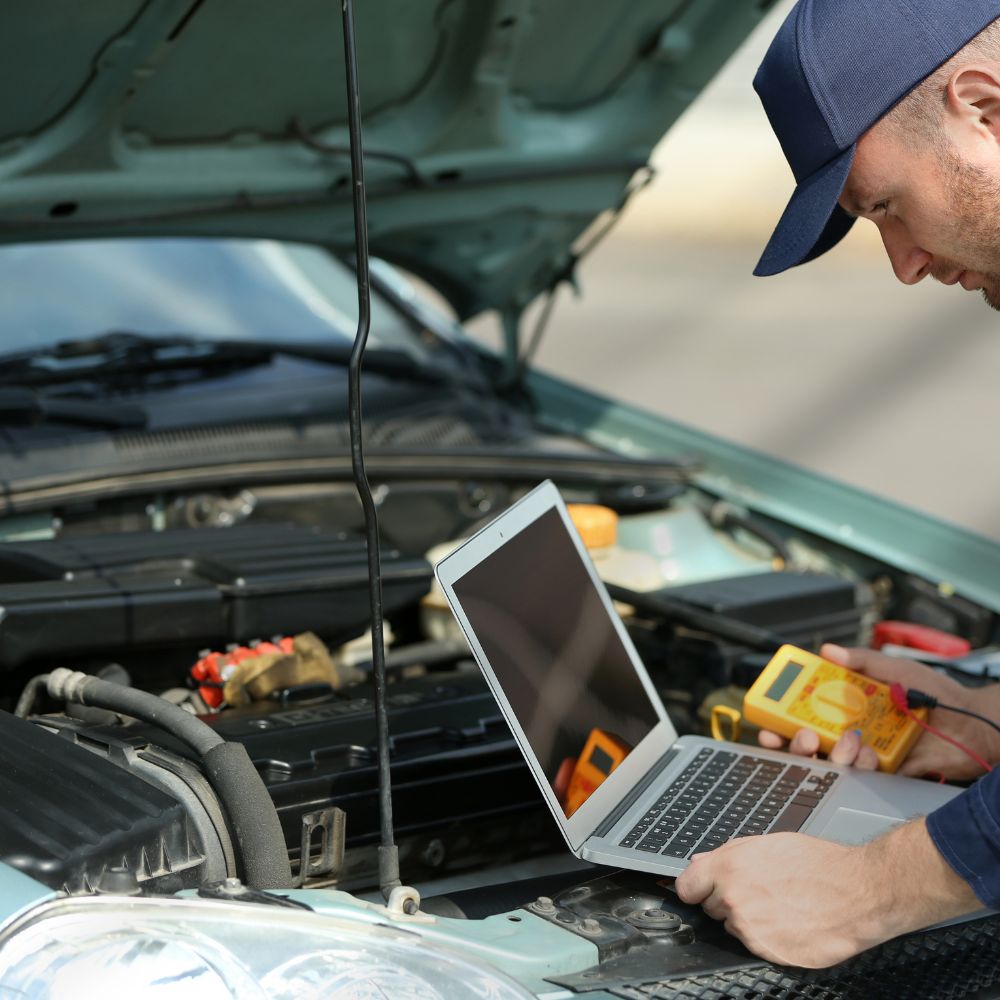 Mechaniker liest Fahrzeugdaten von einem Diagnosegerät ab, das an ein Auto angeschlossen ist.